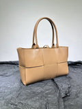 Beige woven leather handbag with double handles on a textured black surface