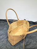 Beige woven leather tote bag with dual handles and spacious suede-lined interior