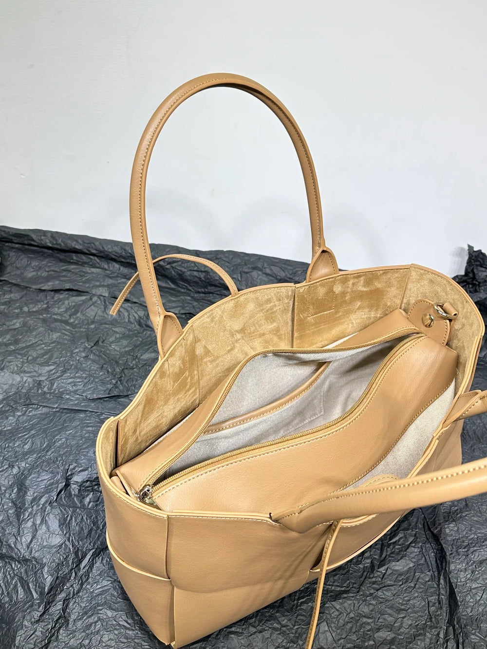 Tan leather tote bag with double handles, interior zipper compartment, and suede lining