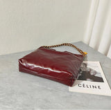 Large quilted calfskin leather shoulder bag in burgundy with gold-tone chain strap on a marble table