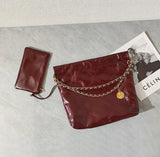 Large burgundy quilted leather shoulder bag with gold chain and matching wallet on marble surface