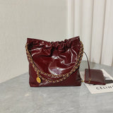 Large burgundy quilted leather shoulder bag with gold chain strap on marble table