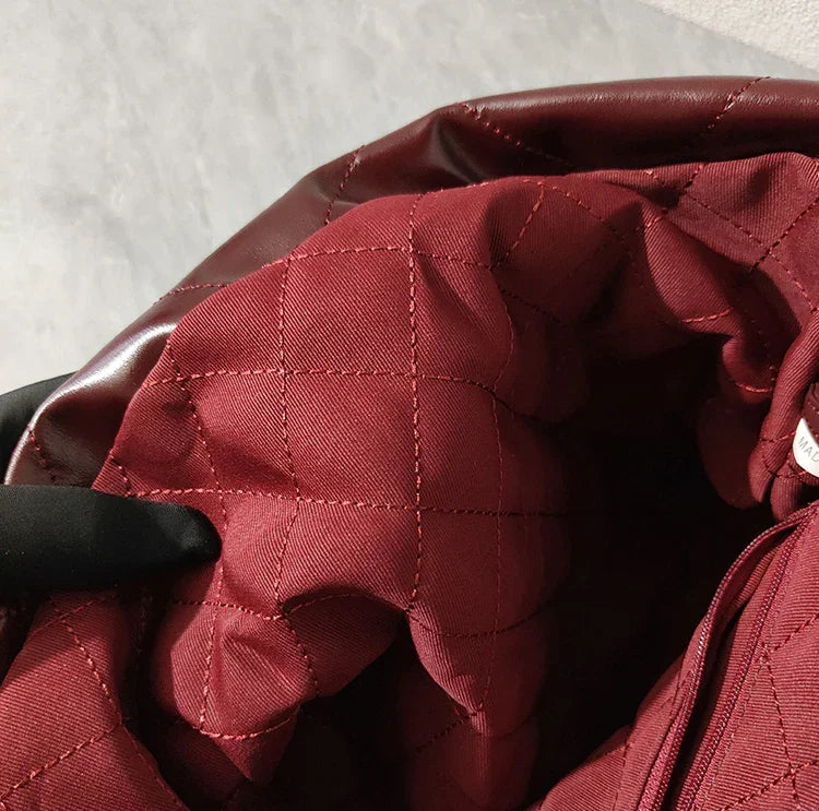 Quilted burgundy fabric interior of large leather shoulder bag with stitched lining