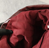 Quilted burgundy fabric interior of large leather shoulder bag with stitched lining
