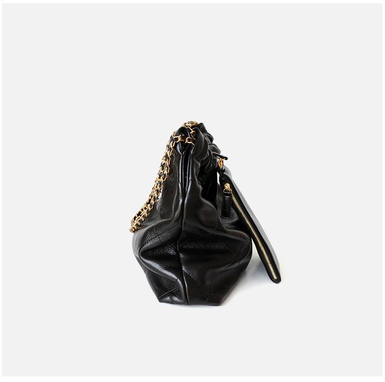 Side view of black leather shoulder bag with gold-tone chain strap and zipper detail