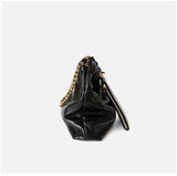 Side view of black leather shoulder bag with gold-tone chain strap and zipper detail