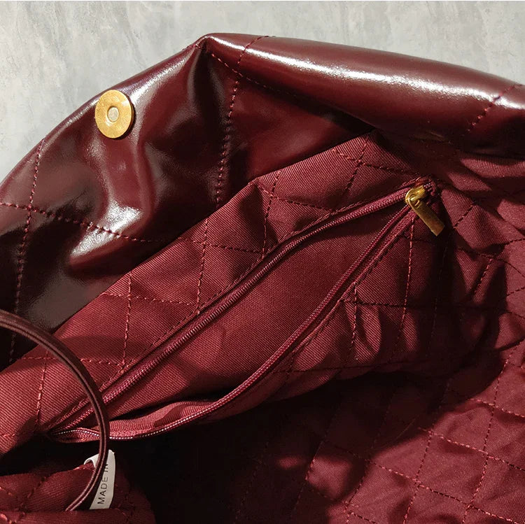 Interior of burgundy quilted leather shoulder bag with gold zipper pocket and snap closure