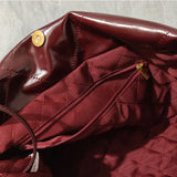Interior of burgundy quilted leather shoulder bag with gold zipper pocket and snap closure