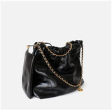 Black calfskin leather shoulder bag with gold chain strap and quilted design on white background
