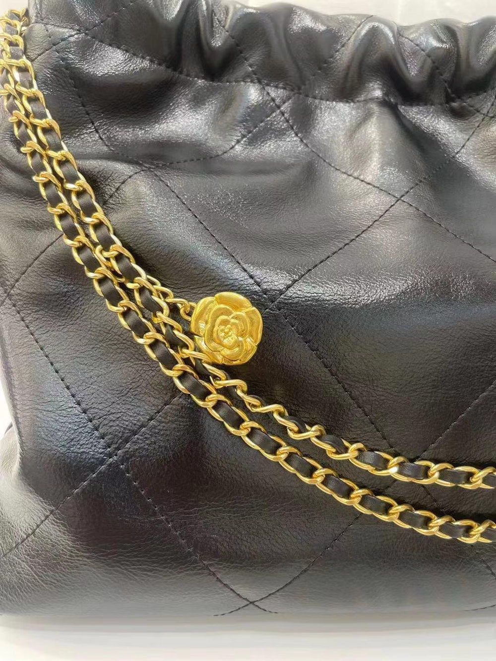 Black quilted leather shoulder bag with gold chain strap and floral gold button detail