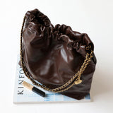 Brown quilted leather shoulder bag with gold chain strap on white surface