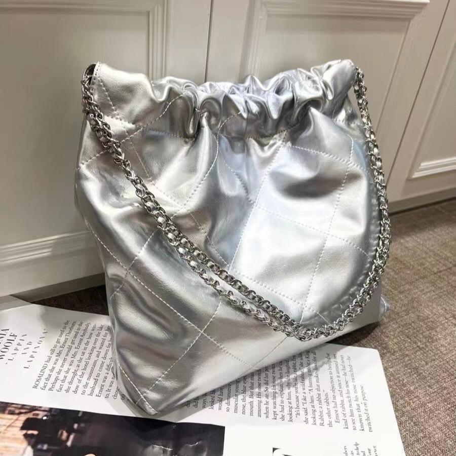 Silver quilted leather shoulder bag with gold-tone chain on a magazine background