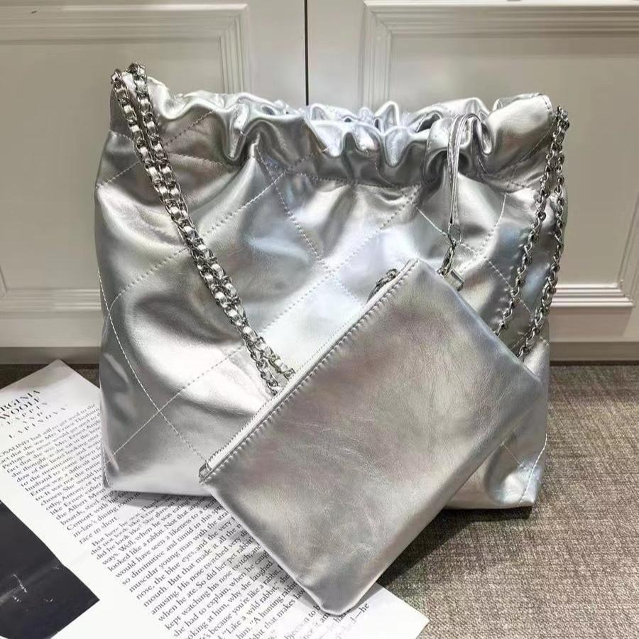 Silver quilted leather shoulder bag with chain strap and matching pouch on neutral background