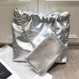 Silver quilted leather shoulder bag with chain strap and matching pouch on neutral background