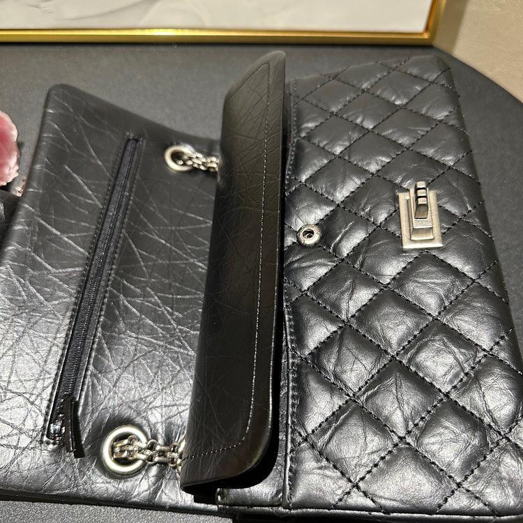 Woman in white outfit carrying a black quilted leather shoulder bag with silver chain strap