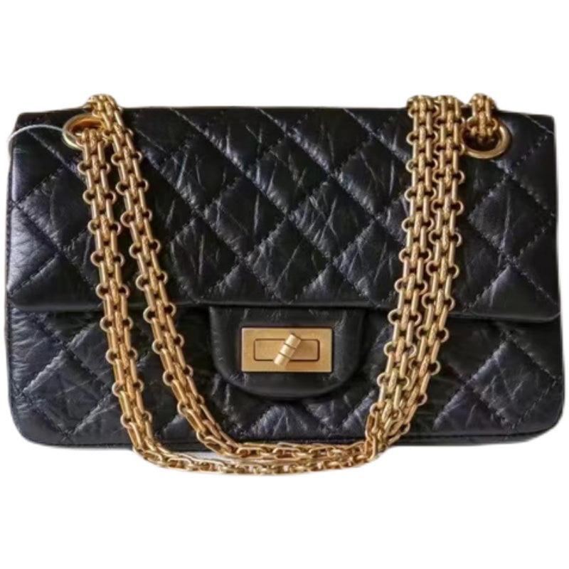 Woman in white shirt carrying black quilted leather shoulder bag with gold chain strap
