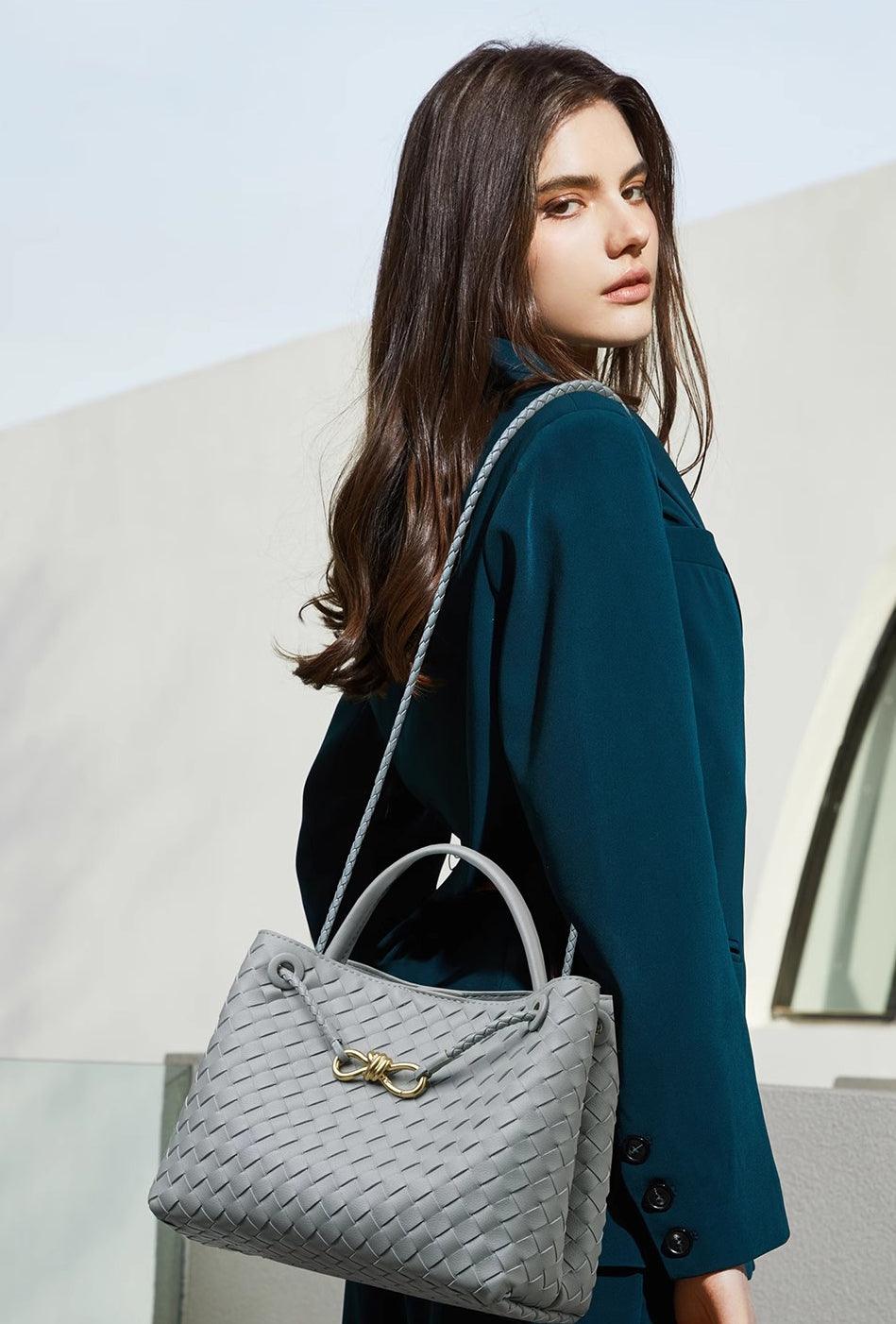 Woman carrying a grey woven leather shoulder bag with metal buckle detail