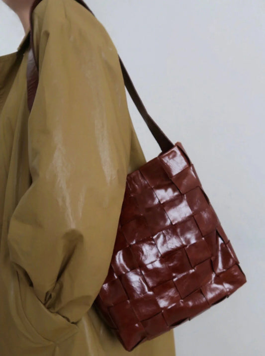 Woman wearing a handwoven chocolate brown cowhide leather bucket bag with shoulder strap