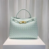 Light blue woven leather shoulder bag with gold metal buckle, displayed on white pedestal