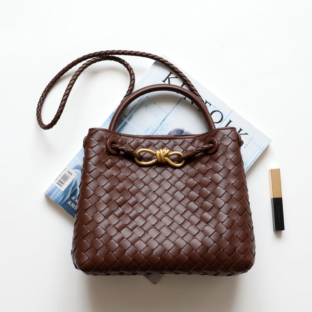 Brown woven leather shoulder bag with gold metal buckle, braided strap, on white background