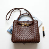 Brown woven leather shoulder bag with gold metal buckle, braided strap, on white background