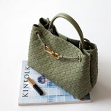 Green cowhide leather woven shoulder bag with gold metal buckle, top handles, on white background