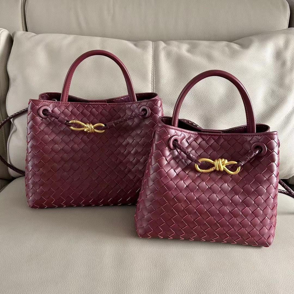 Burgundy woven leather shoulder bags with gold metal buckles on a beige sofa.