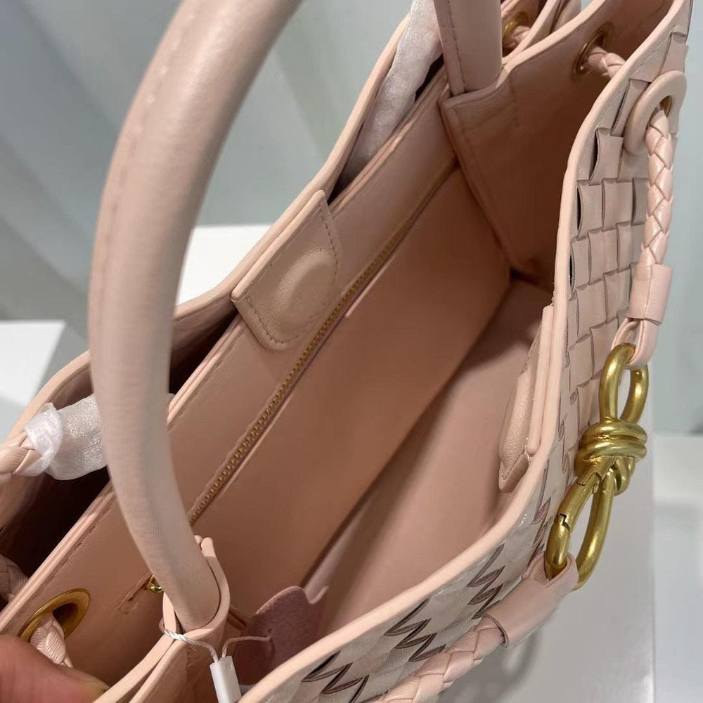 Pink cowhide leather woven shoulder bag with gold buckle, top handle, and zip pocket