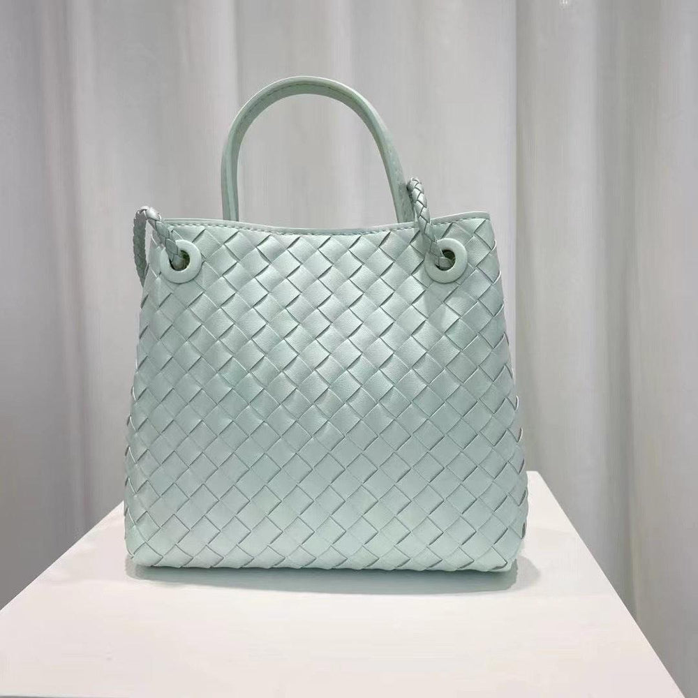 Light blue woven cowhide leather shoulder bag with double handles on display