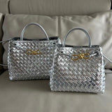 Silver woven leather shoulder bags with gold metal buckle and top handles on beige sofa