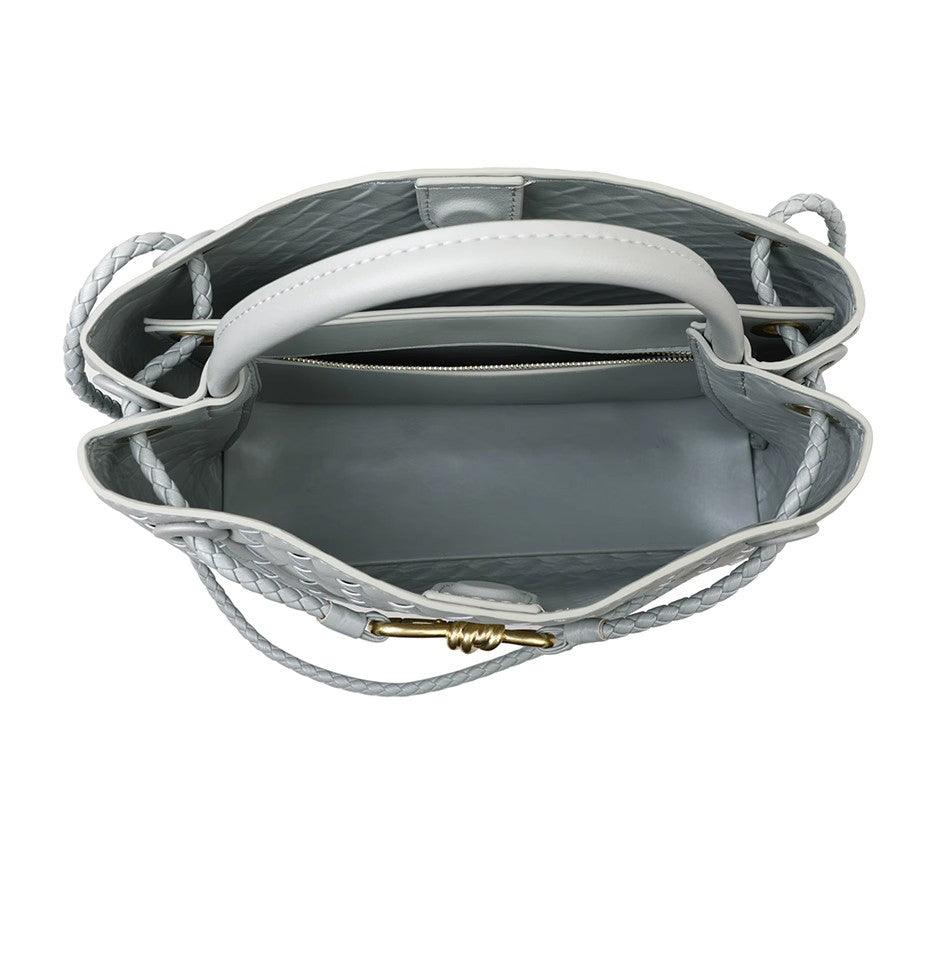 Interior view of woven cowhide leather shoulder bag with metal buckle, zip pocket, and braided handles.