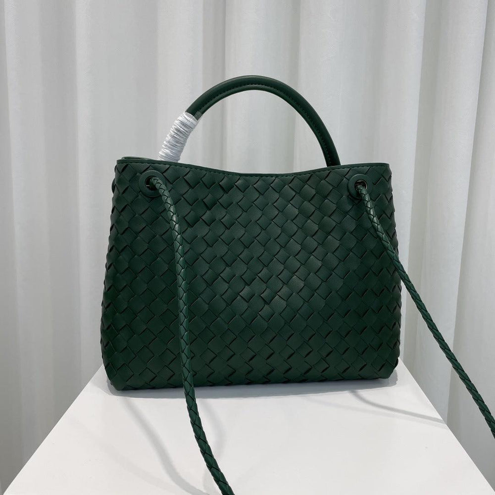 Dark green woven leather shoulder bag with knotted straps on a white table, designer style