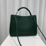 Dark green woven leather shoulder bag with knotted straps on a white table, designer style