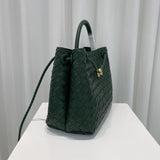 Dark green woven leather shoulder bag with braided strap and gold metal buckle on display