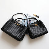 Black woven leather shoulder bags with gold metal buckles on a white background