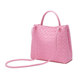 Pink woven leather shoulder bag with braided strap and top handle, fashion handbag on white background