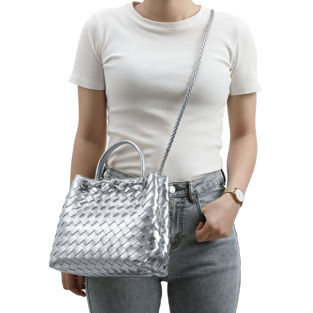 Woman wearing a metallic silver woven leather shoulder bag with handles and crossbody strap