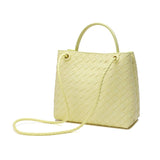 Woven yellow leather shoulder bag with knotted strap and metal eyelets on white background