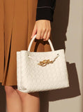 White woven cowhide leather shoulder bag with gold metal buckle, held by a woman