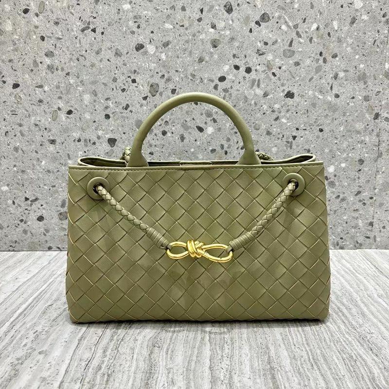 Olive green woven leather shoulder bag with braided handle and gold metal buckle on a stone background