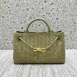 Olive green woven leather shoulder bag with braided handle and gold metal buckle on a stone background