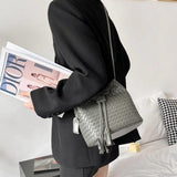 Woman carrying woven lambskin leather bucket bag with drawstring and shoulder strap