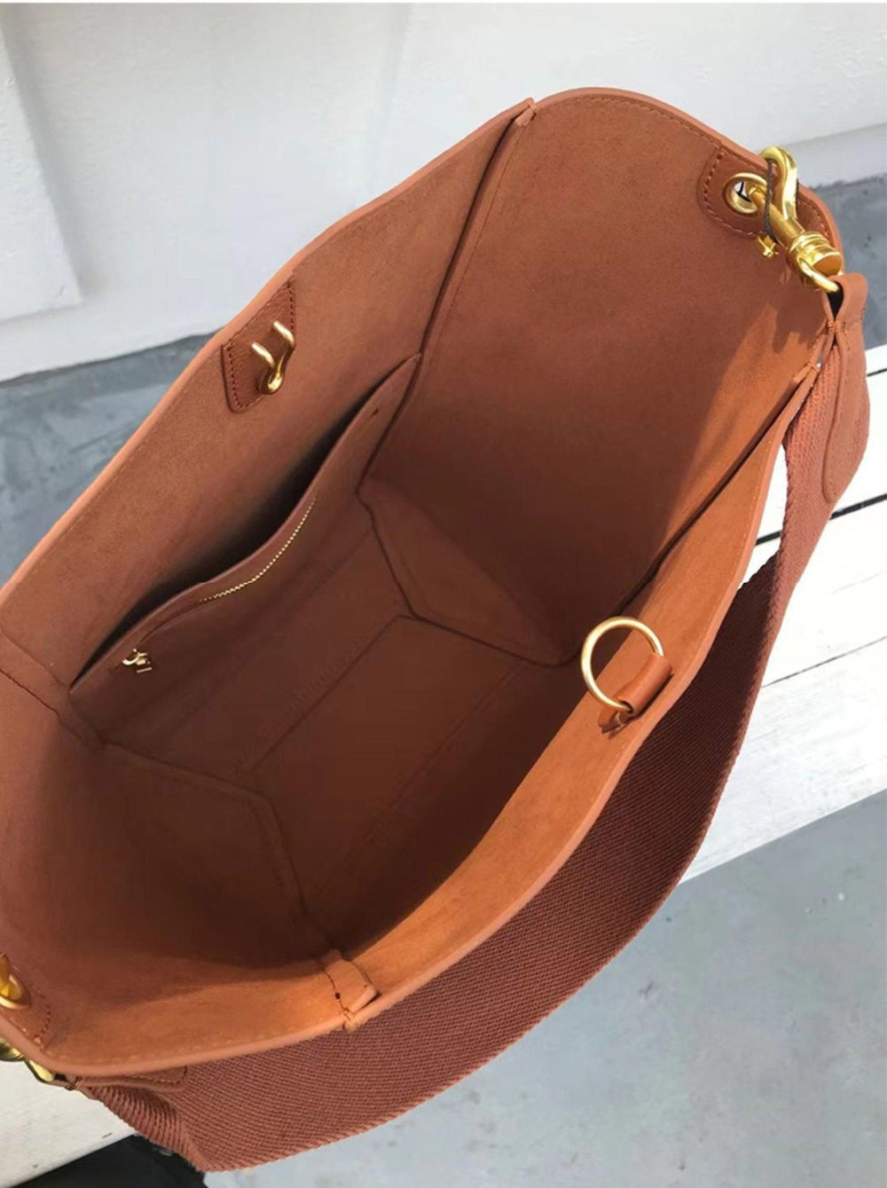 Interior of brown genuine leather bucket bag with gold hardware and zip pocket