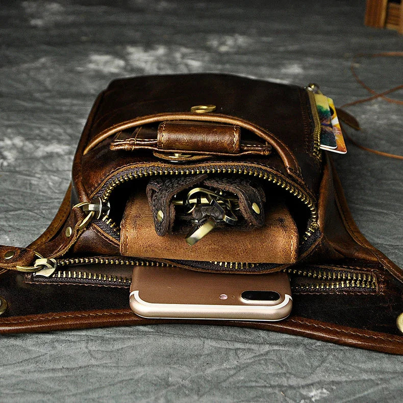 Full grain dark brown leather leg bag with zipper pockets and metal rivet details