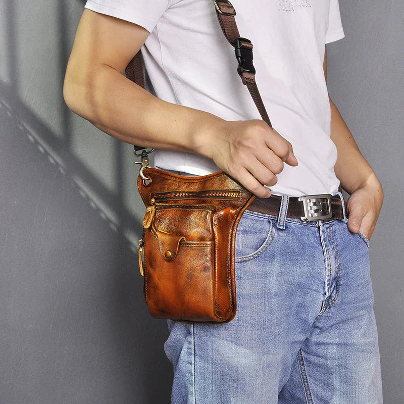 Brown full grain leather leg bag with multiple pockets worn crossbody by a man in jeans