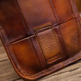 Close-up of brown full grain leather bag with visible stitching on wooden surface