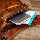 Full grain brown leather leg bag with zipper pocket holding a smartphone and small pouch