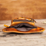 Open brown full grain leather waist bag with zippers, displayed on rustic wooden surface