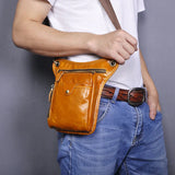 Tan full grain leather leg bag worn crossbody, featuring multiple zippered pockets.