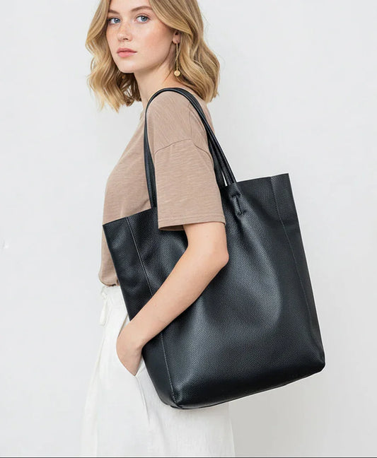 Woman carrying a large black leather tote bag, stylish handbag for women